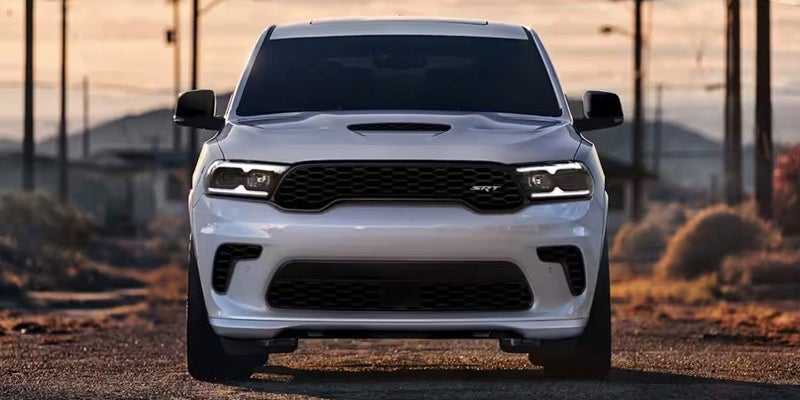 An image of a white Dodge Durango, facing the camera head-on, on a desert road. 