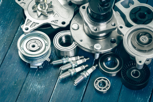 An image of random brand new car parts spread out on a gray wooden table.