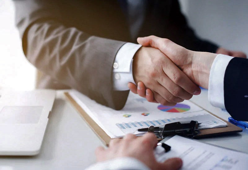 Two people shaking hands over a sealed deal for a new car. 