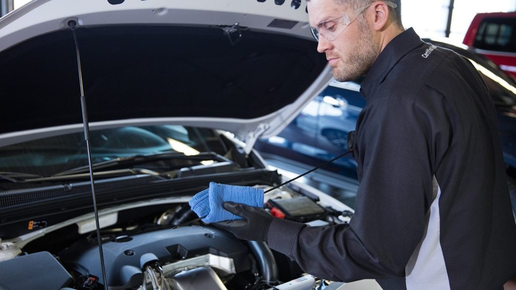 A service technician performing full service on a car engine.