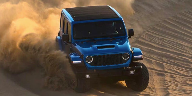 A Wrangler kicking up dust as it tackles dunes